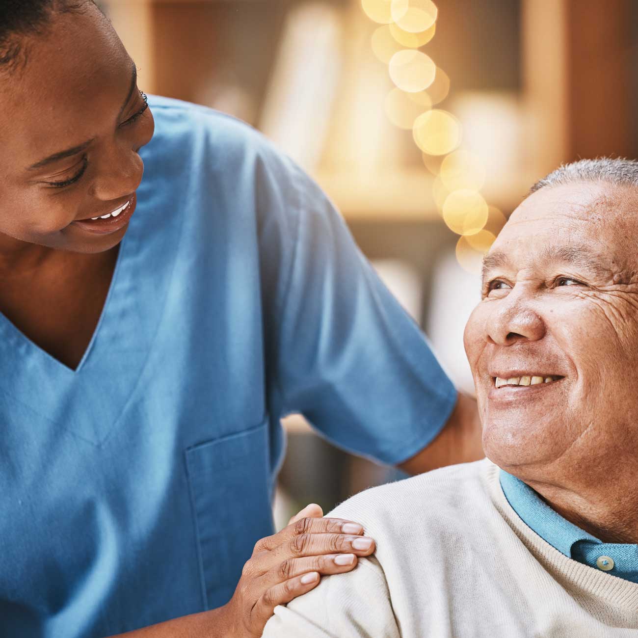 Personal aide in Brooklyn sharing a warm moment with an elderly man, providing non-medical companion care with a reassuring touch and a friendly smile.